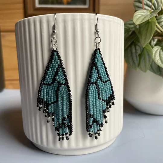 Unique earrings feature intricate beadwork, capturing the delicate charm of butterfly wings in matte teal