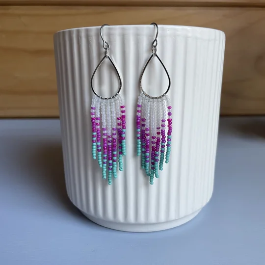 These distinctive earrings seamlessly blend geometric precision with a touch of cool sophistication. The silver tear drop add a contemporary edge, while the colored beads infuse a subtle pop of color, creating a unique and eye-catching accessory.

frosted white, magenta, aqua