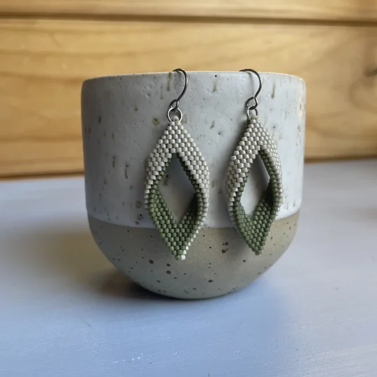matte green and beige
 handwoven earrings feature a unique twisted marquise shape, combining clean lines with a gentle three-dimensional curve. Their open design adds a sense of lightness and movement, making them a subtle statement piece for any outfit. Crafted with precision using high-quality Miyuki Delica beads, they’re lightweight, comfortable to wear, and perfect for everyday style or special occasions.