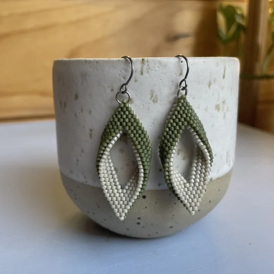 matte green and beige
 handwoven earrings feature a unique twisted marquise shape, combining clean lines with a gentle three-dimensional curve. Their open design adds a sense of lightness and movement, making them a subtle statement piece for any outfit. Crafted with precision using high-quality Miyuki Delica beads, they’re lightweight, comfortable to wear, and perfect for everyday style or special occasions.