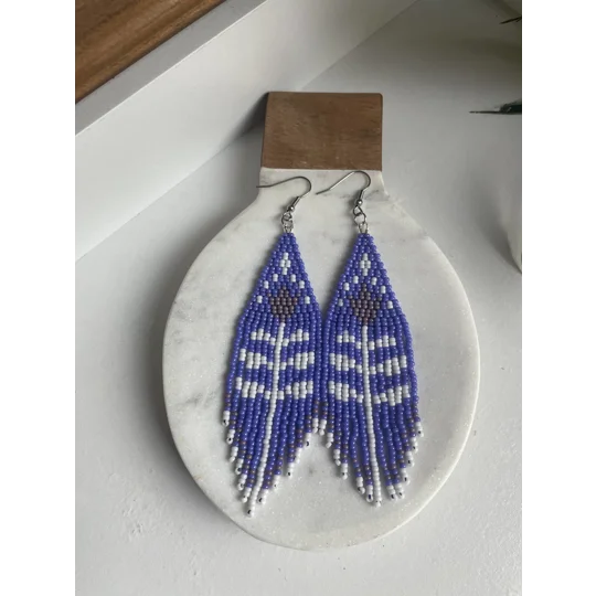 A pair of handmade beading earrings. In purple with a white tulip flower with mauve coloured petals