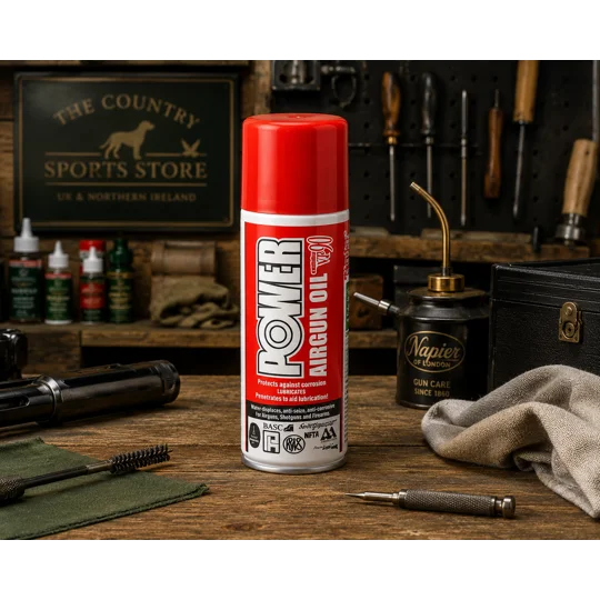 Napier Power Airgun Oil aerosol can displayed on a traditional gunsmith's workbench with air rifle maintenance tools in a country sports workshop.