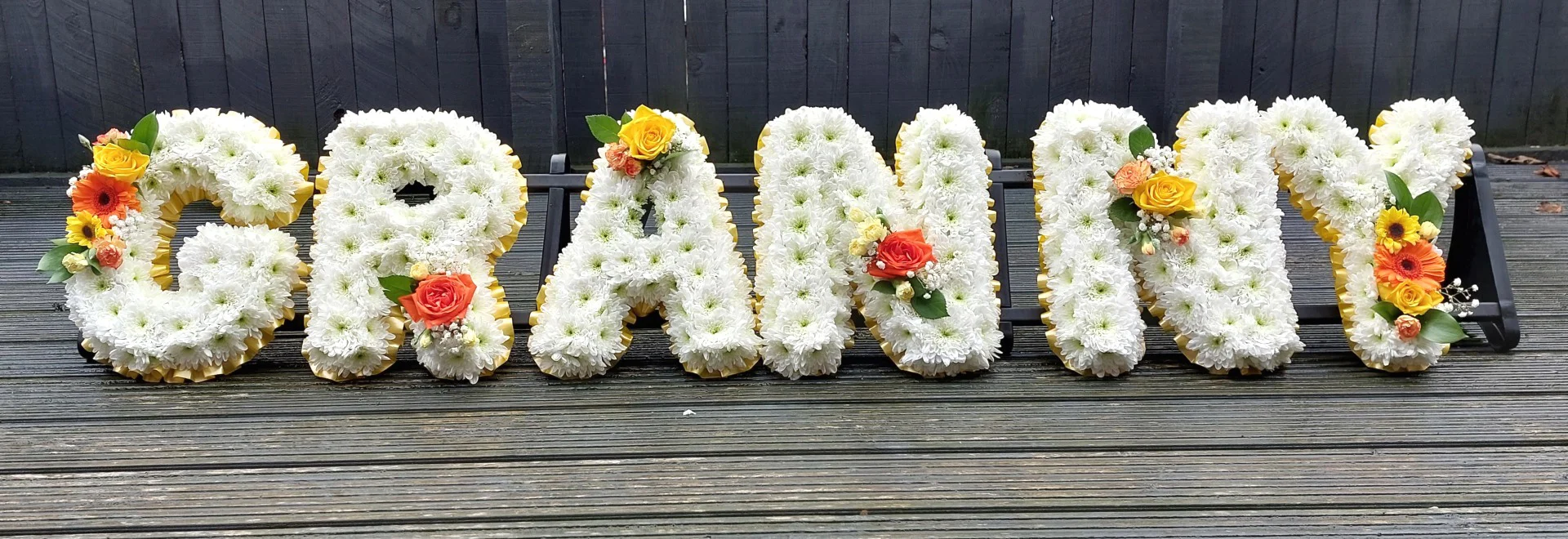 funeral flower letters in white with orange and yellow flowers