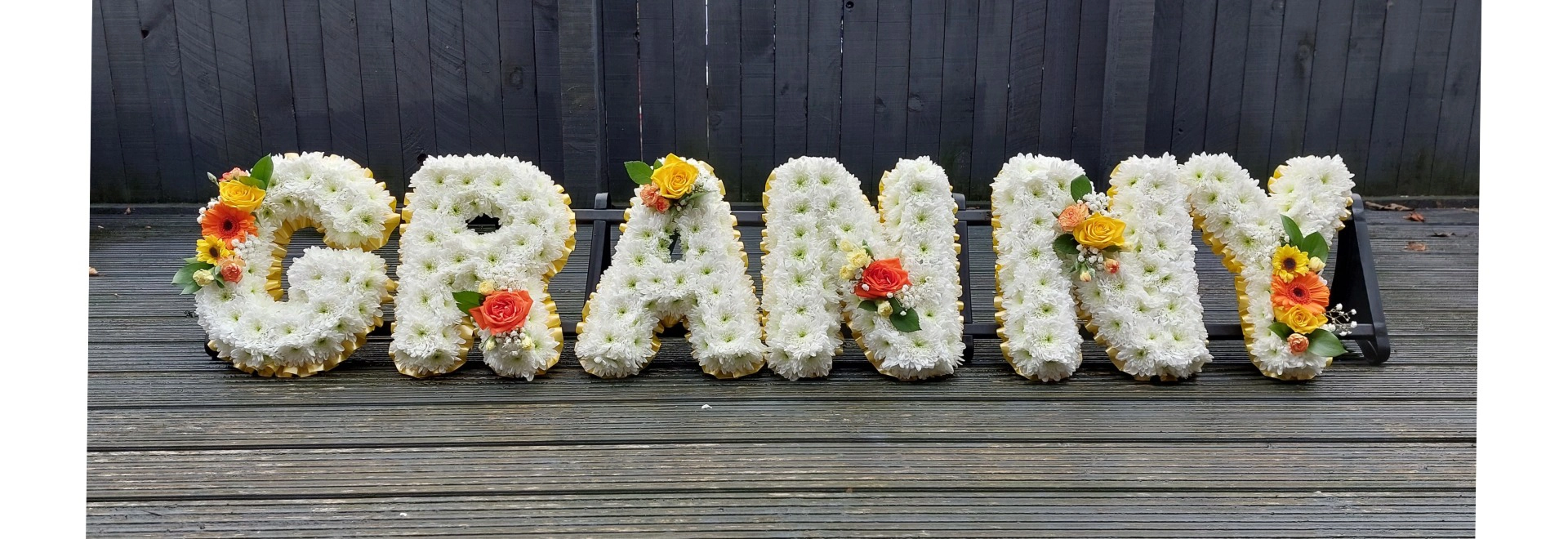 funeral flower letters in white with orange and yellow  flowers