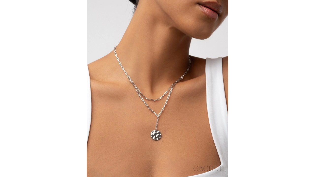 the necklace Motive layers elongated links and a sculpted, hammered medallion